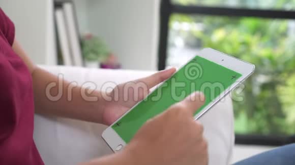 年轻的亚洲女性使用带有绿色屏幕的黑色平板设备视频的预览图