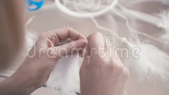 雌性手的特写将白色羽毛和珠子粘在线上视频的预览图