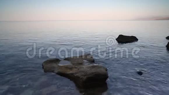 平静的海浪田园诗般的沙滩碧蓝的海水蓝天白云石头鹅卵石视频的预览图