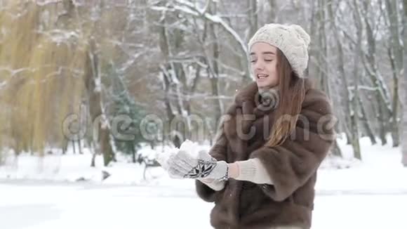 快乐的年轻女孩在公园里吐着雪和笑慢慢地视频的预览图