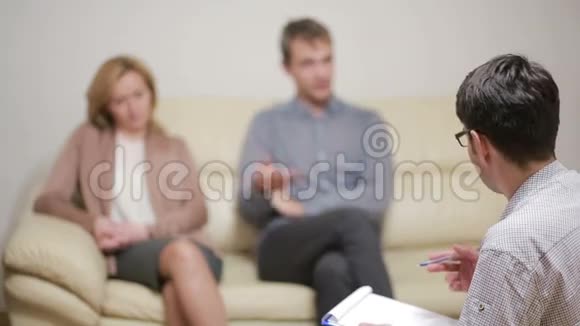 男性心理学家帮助忧心忡忡的年轻夫妇家庭治疗愤怒的人视频的预览图