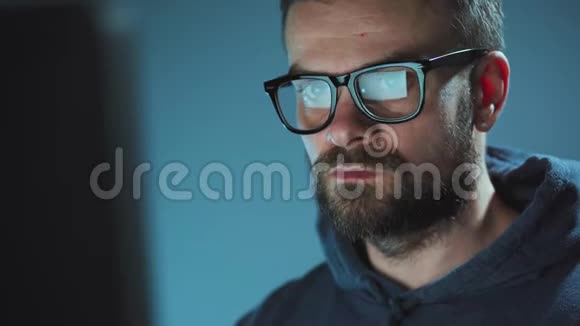 戴眼镜的男性黑客在黑暗的办公室里用电脑工作网络犯罪概念视频的预览图