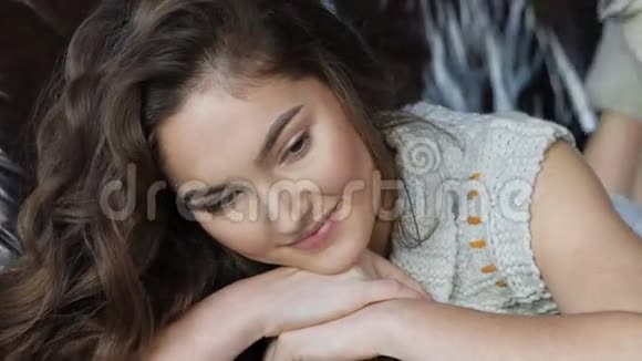 漂亮的女孩在皮革沙发上放松和微笑视频的预览图