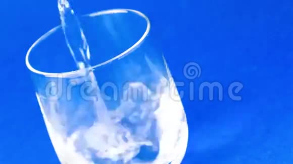 在蓝色背景下用水填充玻璃的顶部视频的预览图