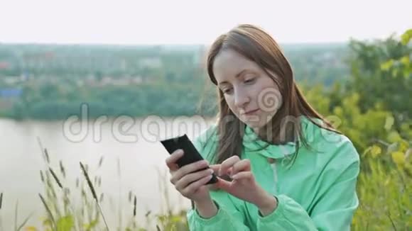 美丽的女孩站在河堤上打着电话视频的预览图