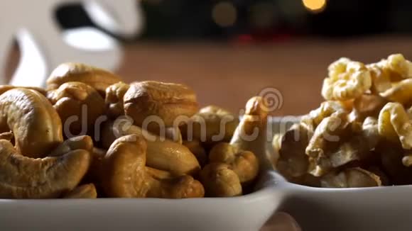 核桃仁腰果和开心果放在木板上的碗里圣诞节背景模糊视频的预览图