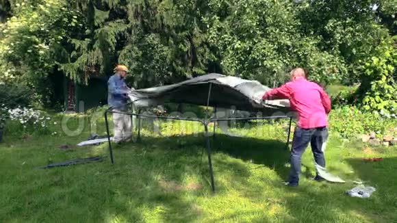 父亲和儿子把帐篷布放在花园屋顶上视频的预览图