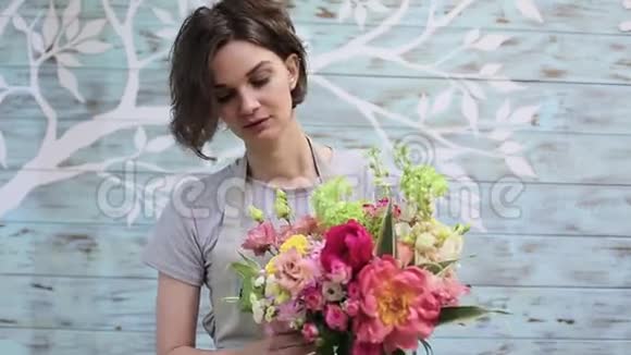 美丽的年轻女花匠拿着花束在墙上视频的预览图