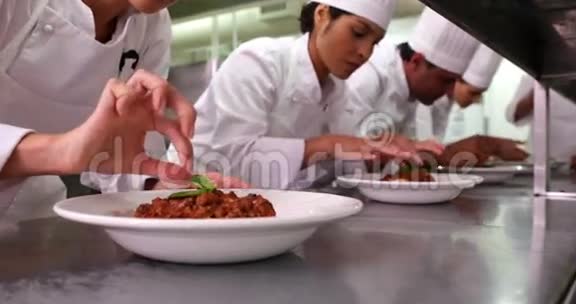 一排厨师装饰意大利面菜视频的预览图