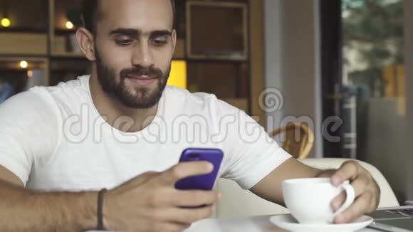 男人一边喝咖啡一边用智能手机视频的预览图