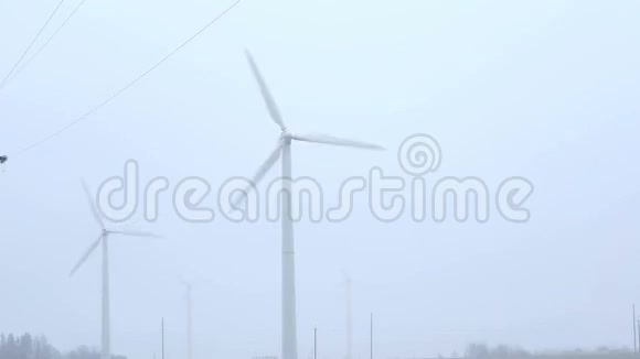 雾蒙蒙的早晨靠近公路的风车视频的预览图