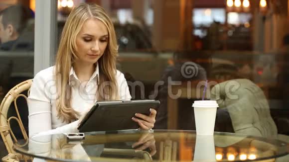 在咖啡馆里使用平板电脑触摸屏的女人视频的预览图