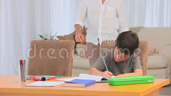 一个黑发小男孩在做作业视频的预览图