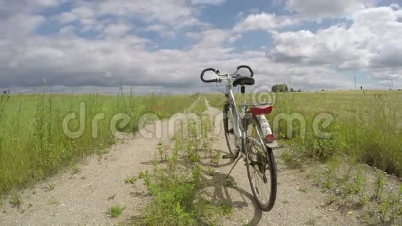 一辆自行车在农村农田上碎石路和云运动延时4K视频的预览图