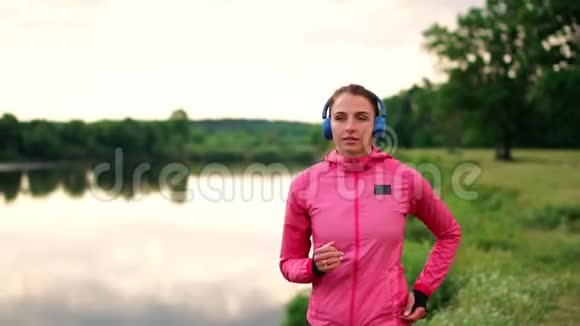 清晨在阳光明媚的黎明时分在池塘附近的公园里慢跑女孩正准备去马里亚诺带领一个健康的人视频的预览图