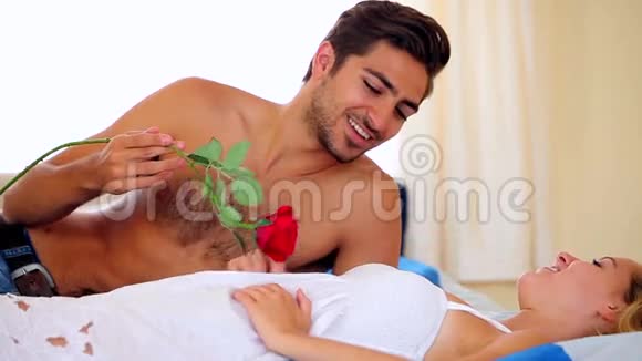 一个男人在床上用红玫瑰搔痒他的女朋友视频的预览图