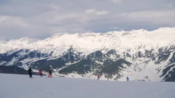 冬季滑雪者和滑雪板上的人在山上滑雪胜地的斜坡上骑马视频的预览图