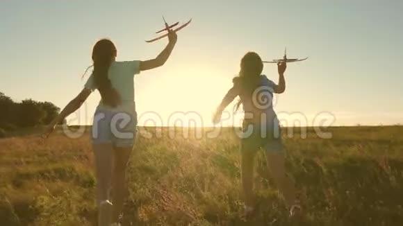 快乐的童年概念飞行的梦想两个女孩在日落时玩玩具飞机以太阳为背景的儿童视频的预览图