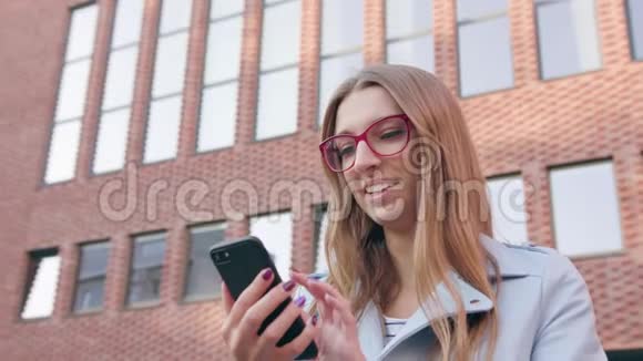 一位年轻女士在大楼附近使用智能手机视频的预览图