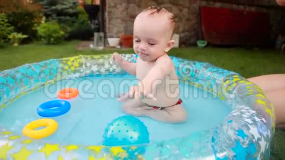 快乐的蹒跚学步的男孩在花园的游泳池里玩得开心视频的预览图