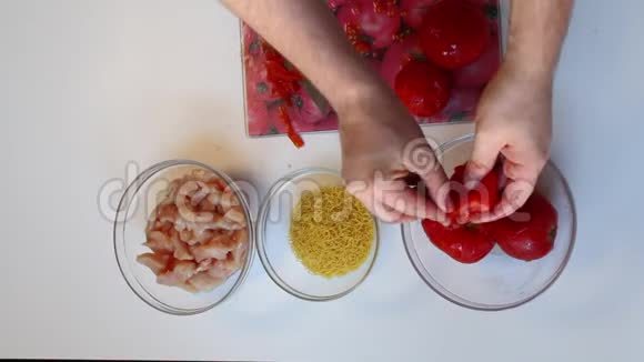 一个人从西红柿里取皮桌子旁边有其他配料粉丝和鸡肉番茄汤的准备视频的预览图