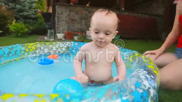 快乐的蹒跚学步的男孩在花园的游泳池里玩得开心视频的预览图