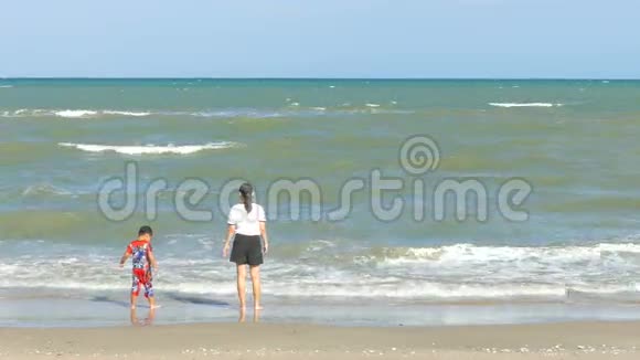 穿着白色T恤的漂亮女人和男孩一起在海滩上散步在泰国玩水非常有趣和放松视频的预览图