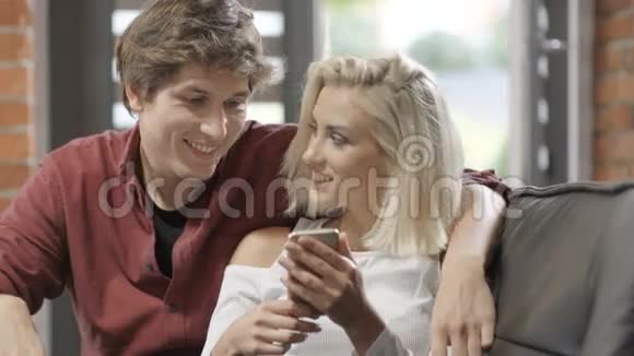 年轻夫妇在现代阁楼内部用手机看照片视频的预览图