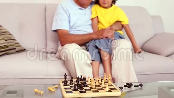 老人坐在沙发上和孙子下棋视频的预览图