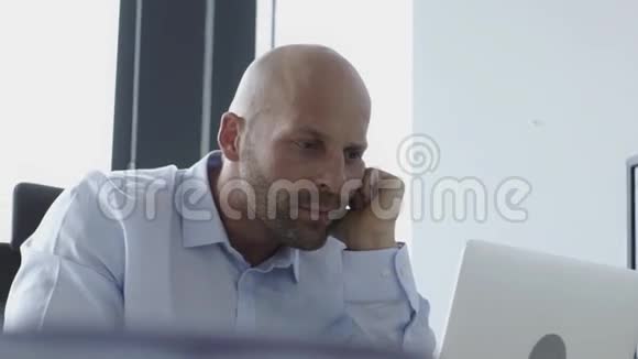 严肃的秃头商人在办公室工作视频的预览图