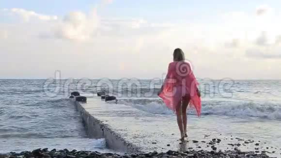 夏天日落时在海滩上散步的女人视频的预览图