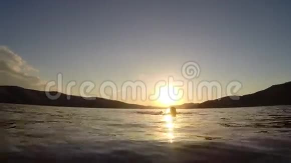 日落时分美丽的女人在海里游泳视频的预览图