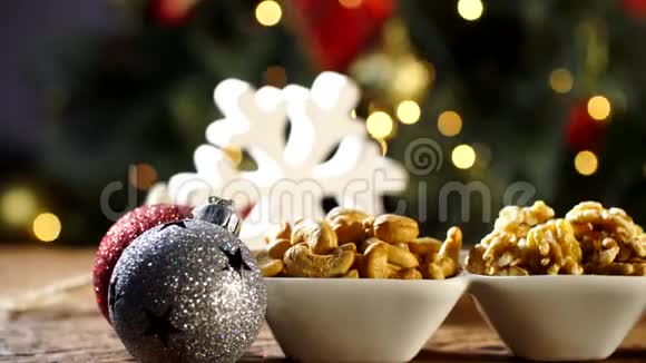 核桃仁腰果和开心果放在木板上的碗里圣诞节背景模糊视频的预览图