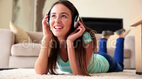 漂亮的黑发女人在地毯上听音乐放松视频的预览图