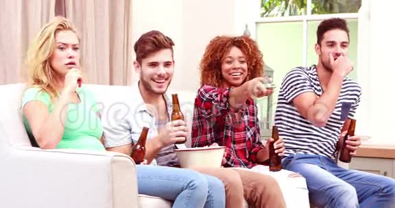 微笑的朋友一边看电视一边吃爆米花一边喝啤酒视频的预览图