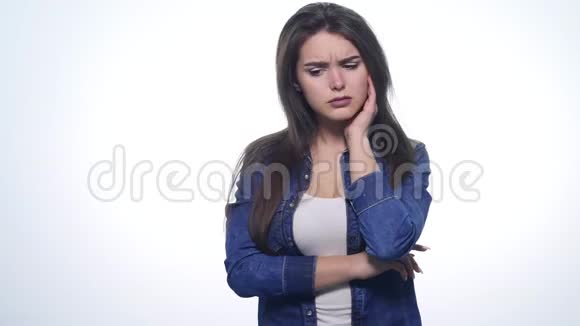 一个可爱的年轻女人在白色的背景下做一张悲伤的脸视频的预览图