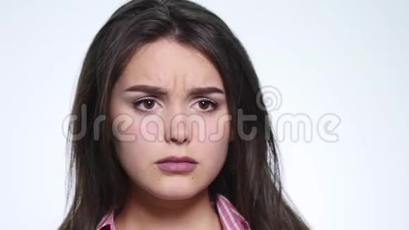 一个可爱的年轻女人在白色的背景下做一张悲伤的脸视频的预览图