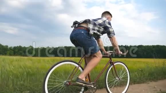 年轻人骑着老式自行车在农村公路的田野运动的家伙骑自行车沿着乡村小径户外男性视频的预览图