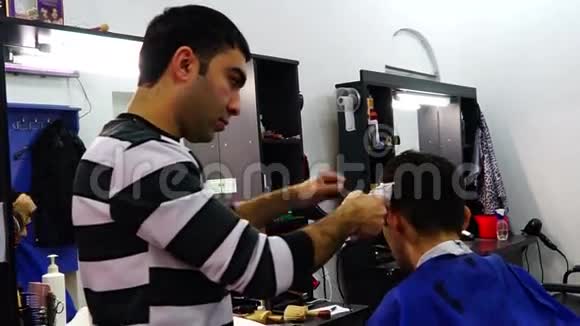 理发师在理发店用剪刀剪客户的头发视频的预览图