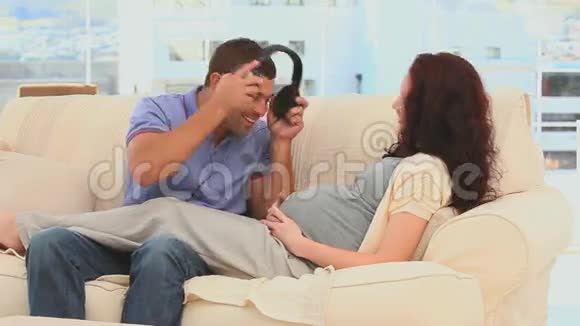 男人把耳机放在妻子的肚子上视频的预览图