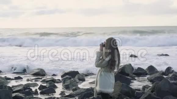 惊涛骇浪的海边的女摄影师拍照留念游客摄影师拍摄海洋图片视频的预览图