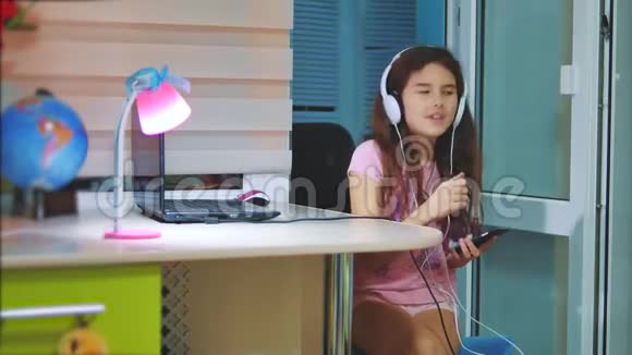 小女孩在智能手机上耳机听音乐青少年生活方式女孩在播放列表音乐视频的预览图