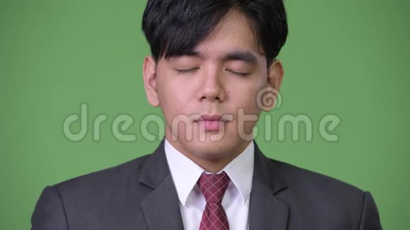 年轻英俊的亚洲商人闭着眼睛放松视频的预览图