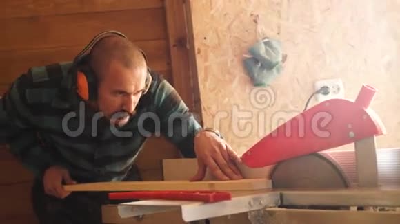 大胆用小胡子木工人用电动夹具锯切木板视频的预览图