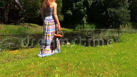 穿着长裙的女孩手提着一篮子水果沿河而行视频的预览图