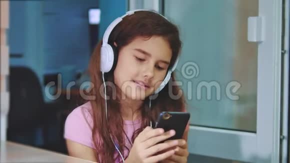 小女孩在智能手机上耳机听音乐青少年女孩在播放列表中的音乐生活方式视频的预览图