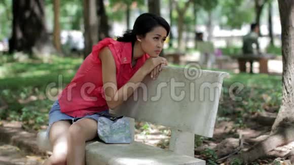 沮丧的女孩坐在公园长凳上视频的预览图