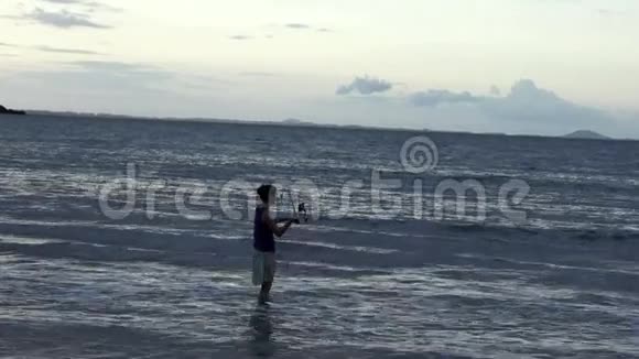 日落时分年轻女子在沙滩上钓鱼视频的预览图