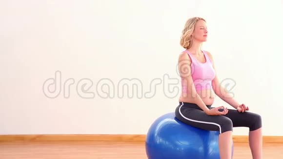 怀孕的金发女郎在健身球上冥想视频的预览图