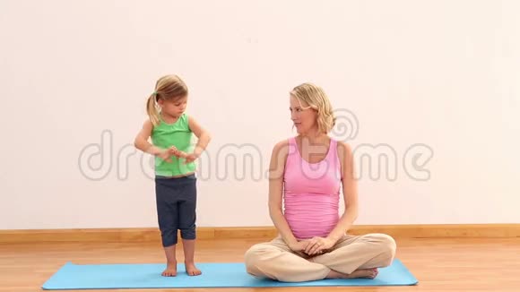 怀孕的母亲和女儿一起做瑜伽视频的预览图